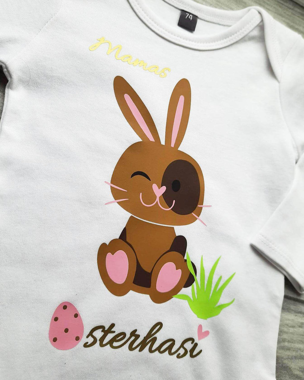 Details Aufruck weißer Babybody mit Osterhase für Ostern in hellbraun und rosa Eier, mit gold metallic Effekt, Papas Osterhasi