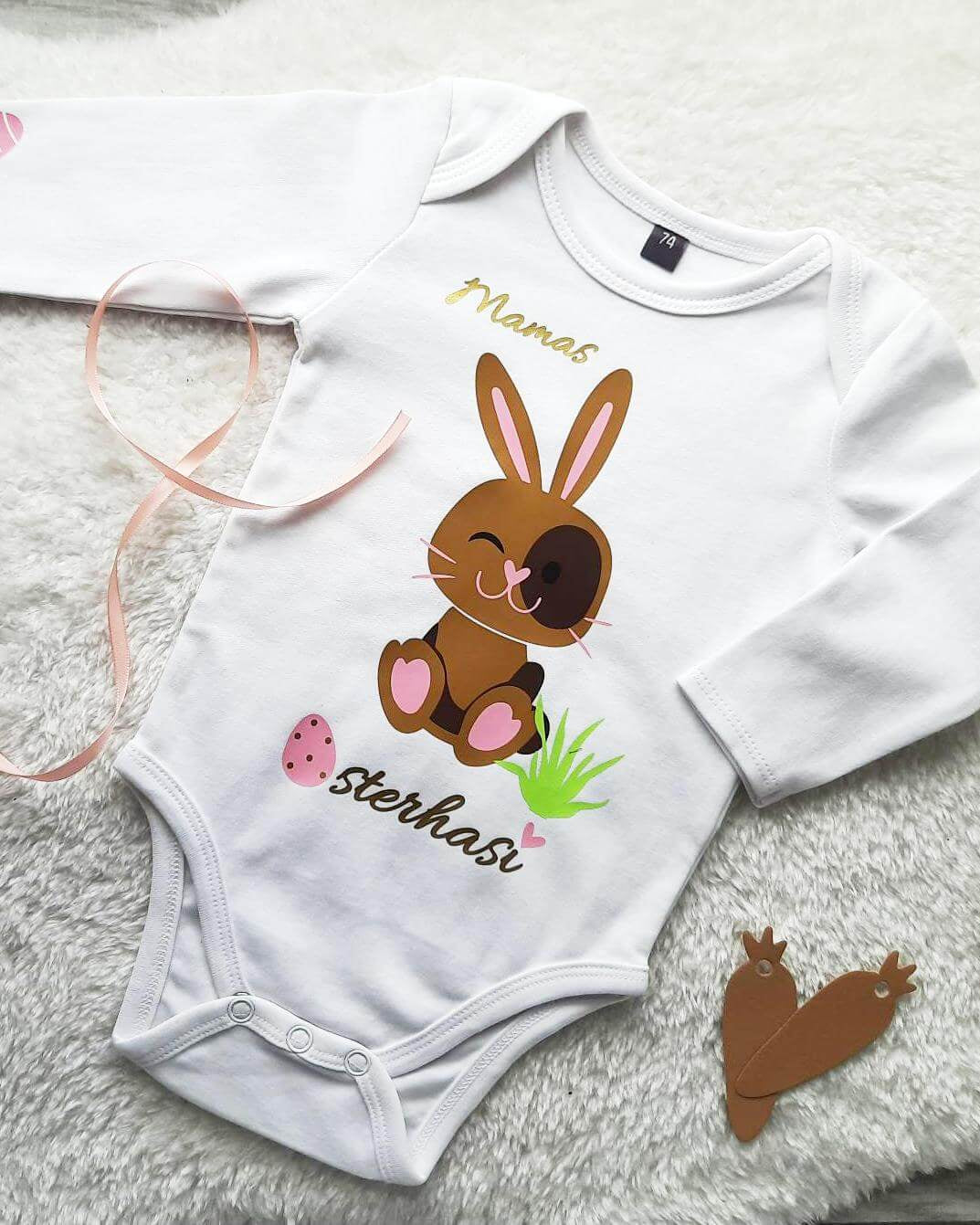 Flatlay weißer Babybody mit Osterhase für Ostern in hellbraun und rosa Eier, mit gold metallic Effekt, Mamas Osterhasi