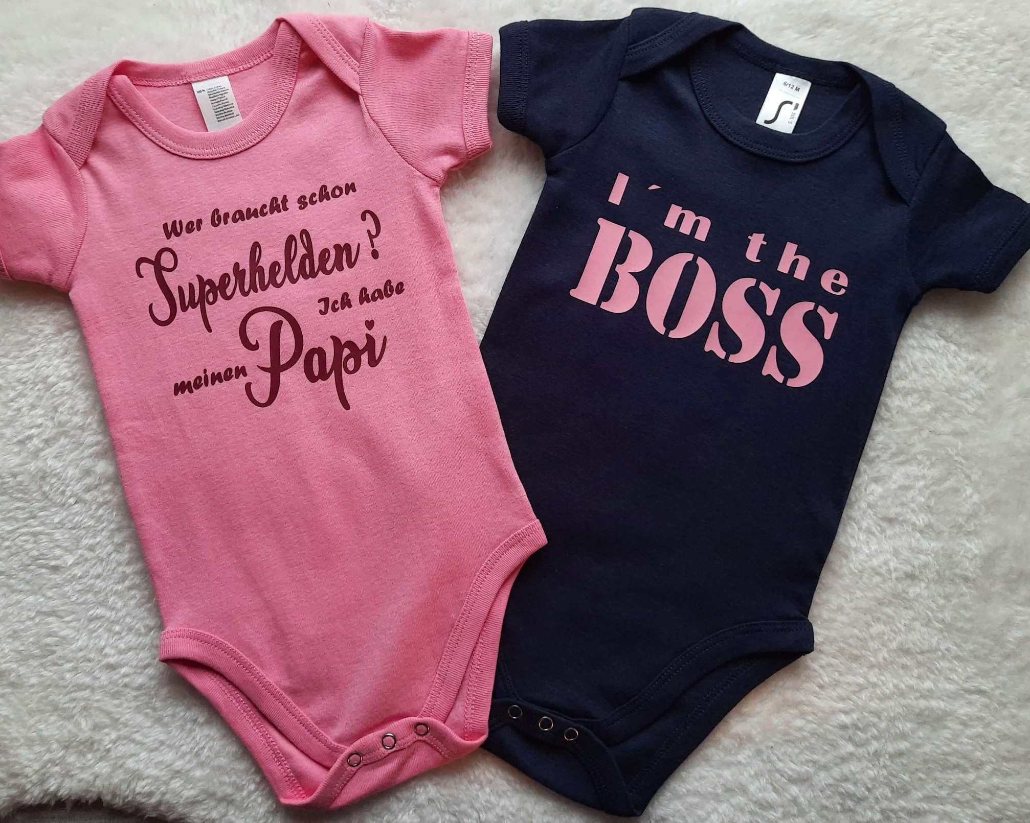 Flatlay zwei Baby Bodys von Smartbabies, Boss und Papa Superheld