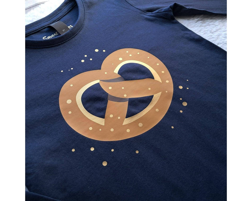 Detailansicht des Aufdrucks, navi farbenes Babyshirt mit Schulterknöpfen, bedruckt mit bayrischer Brezel und gold Tupfen