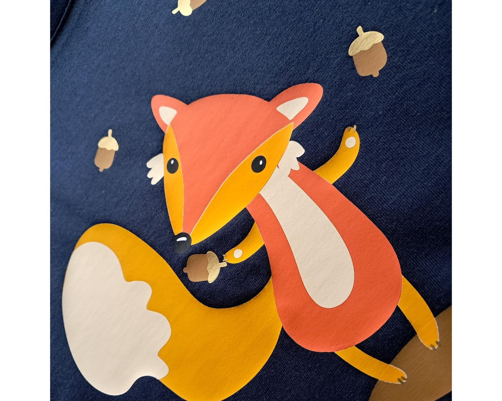 Detailansicht Aufdruck, navi farbenes Geburtstagsshirt für erste Geburtstage, bedruckt mit süßem Fuchs, der Eicheln jongliert und herbstlicher Szene