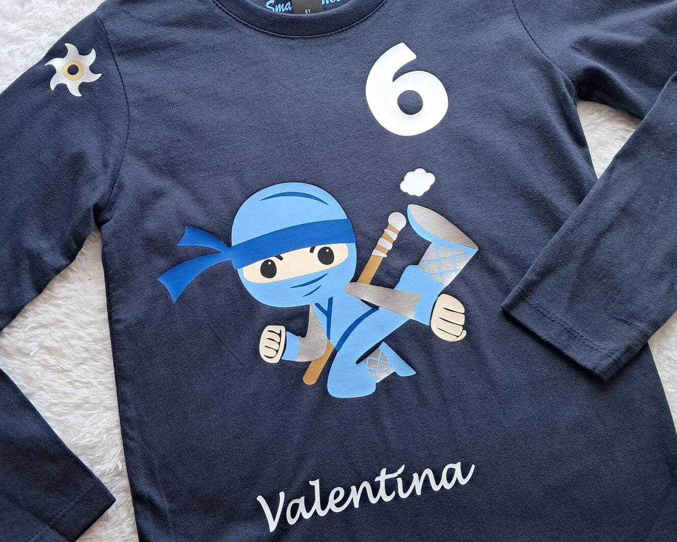 Detail navi Geburtstagsshirt für Kinder mit hellblauem, springendem Ninja, Name und Zahl, mit gold und silber metallic, mit langem Arm