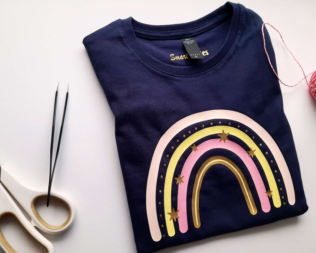 Flatlay navi farbenes Kindershirt bedruckt mit pastelligem Regenbogen, Sonne und Wolke