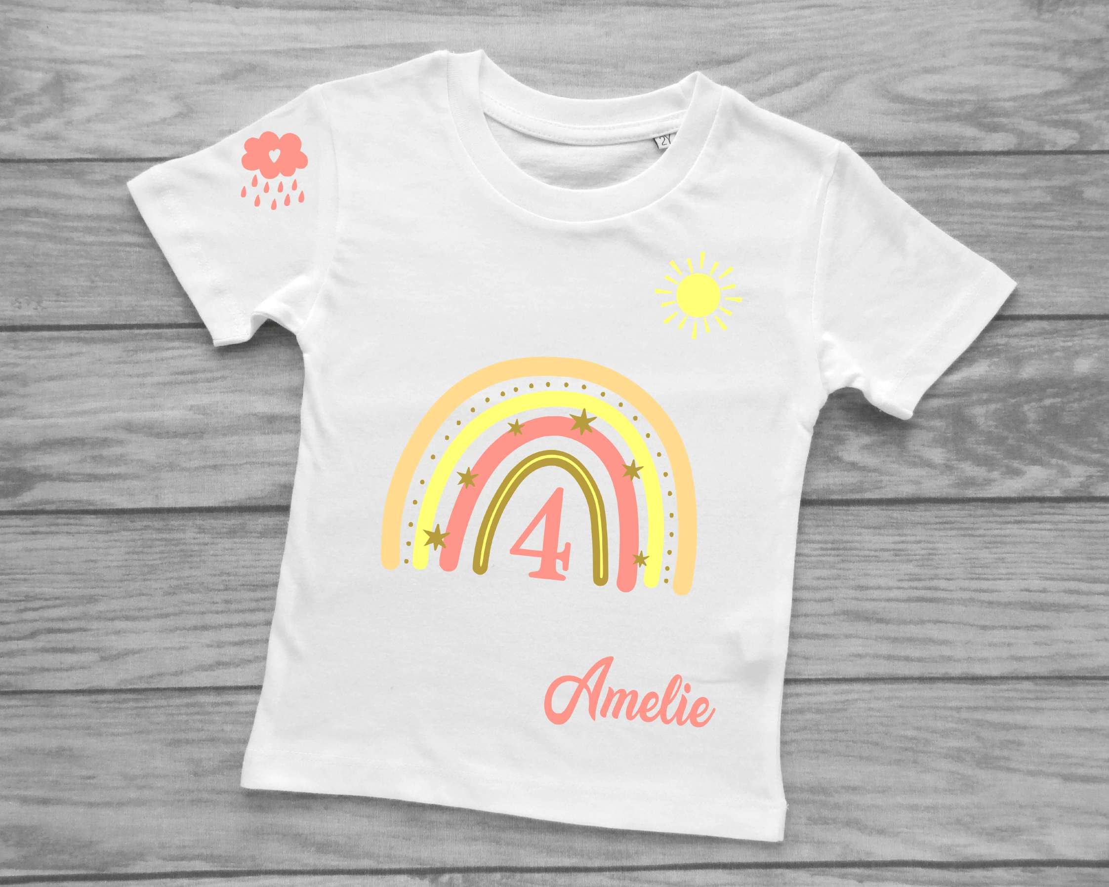 Kinder-Kurzarmshirt in weiß für Geburtstag mit pastell-rosa Regenbogen, Name und Zahl, Sonne und Wolke bedruckt