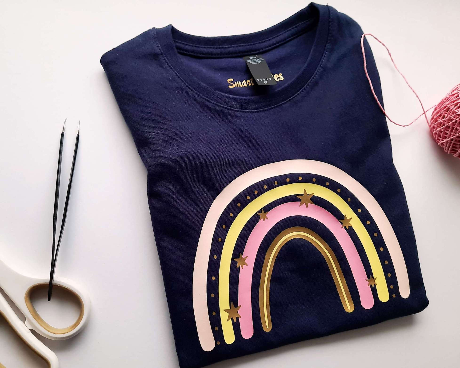 Flatlay gefaltetes navi Geburtstagsshirt Regenbogen in pastell rosa und mit gold metallic Effekt