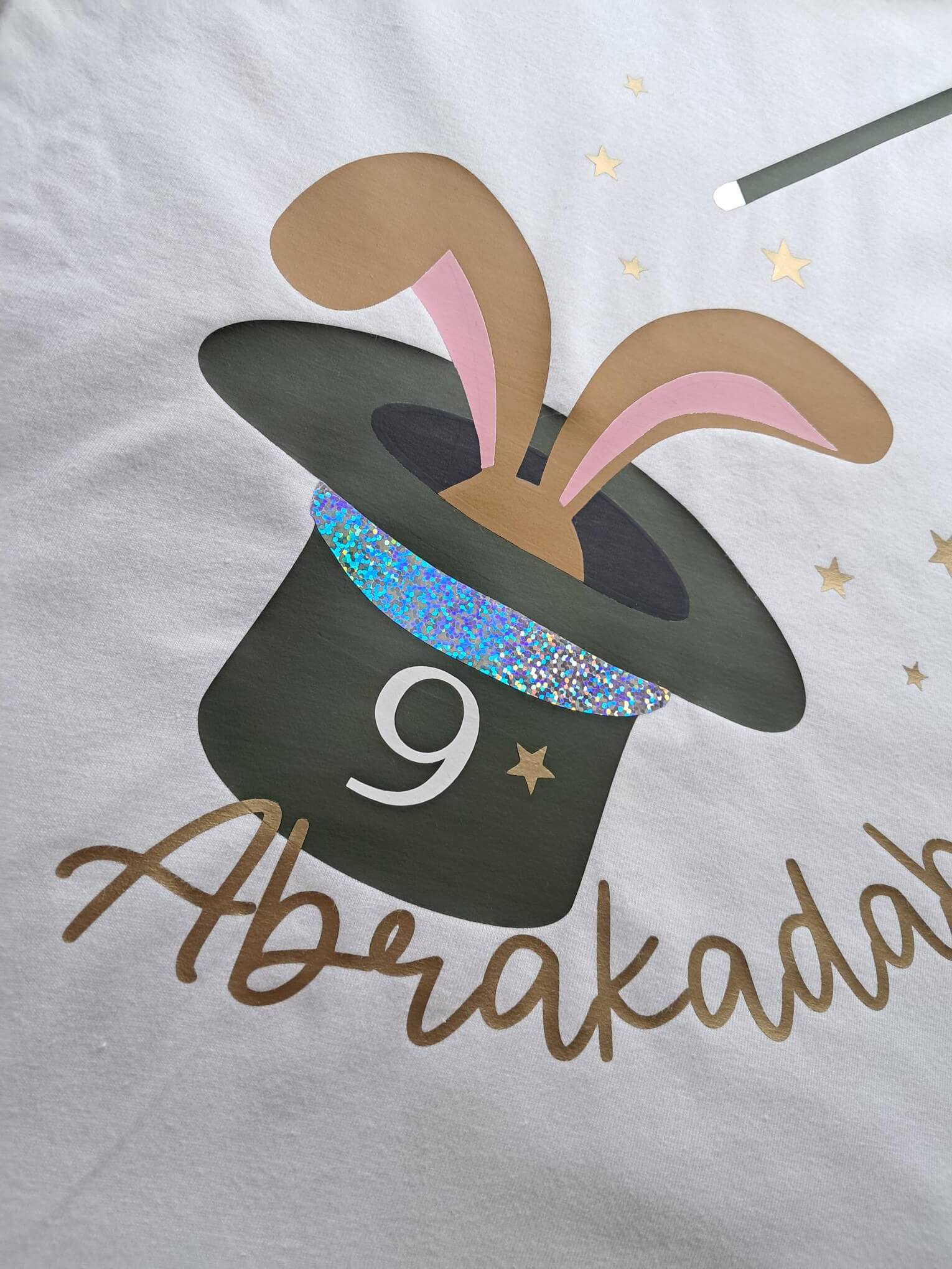 weiteres Detail holhgrahischerAufdruck, weißes Kinder-T-Shirt mit Zauberhut und Hase, magischem holographischem Effekt bedruckt, mit Name und Zahl