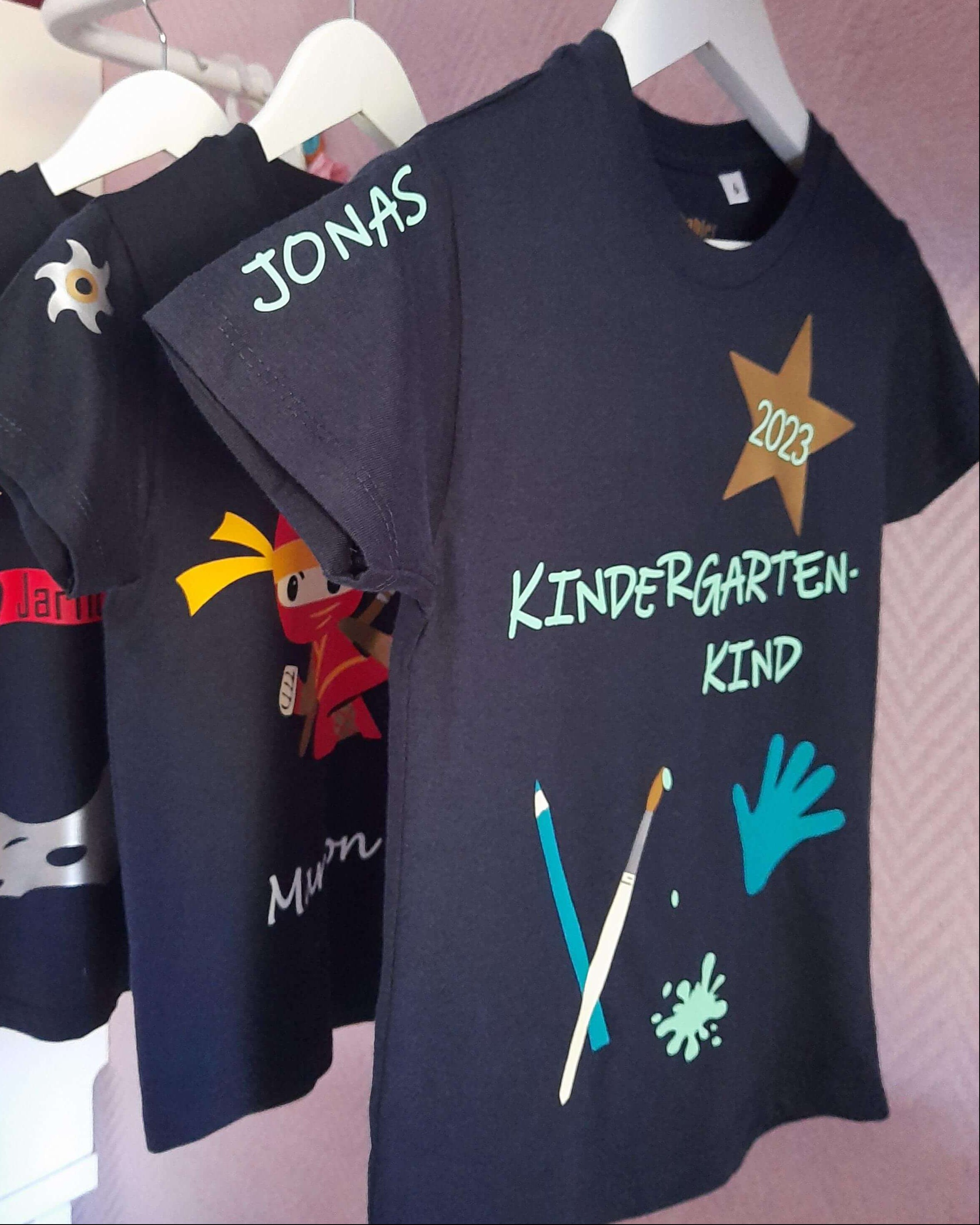 Auswahl bedruckte Kindershirts auf Kleiderstange mit Name und Zahl von Samrtbabies