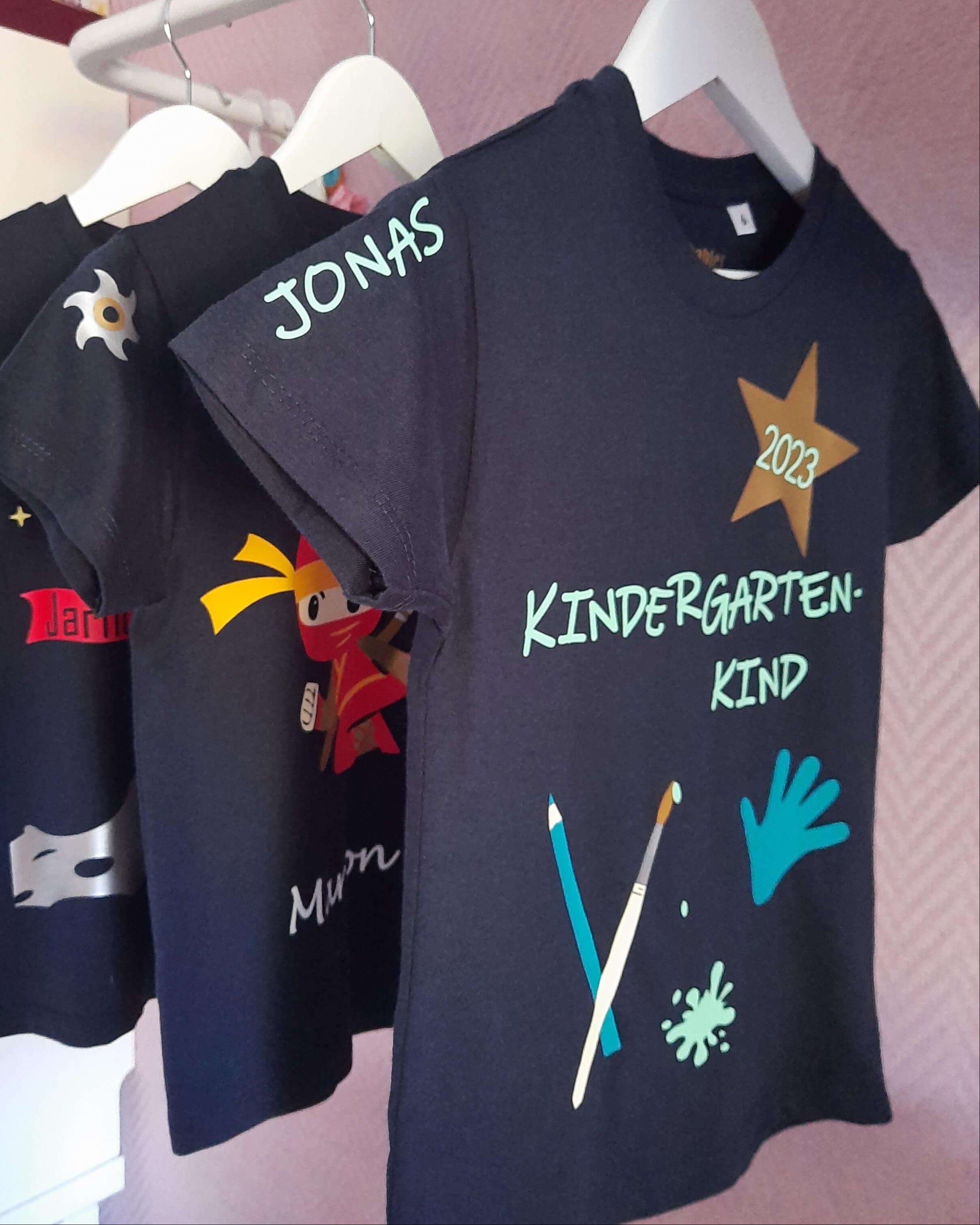 Auswahl bedruckter Kindershirts mit Name und Zahl von Smartbabies auf Kleiderstange