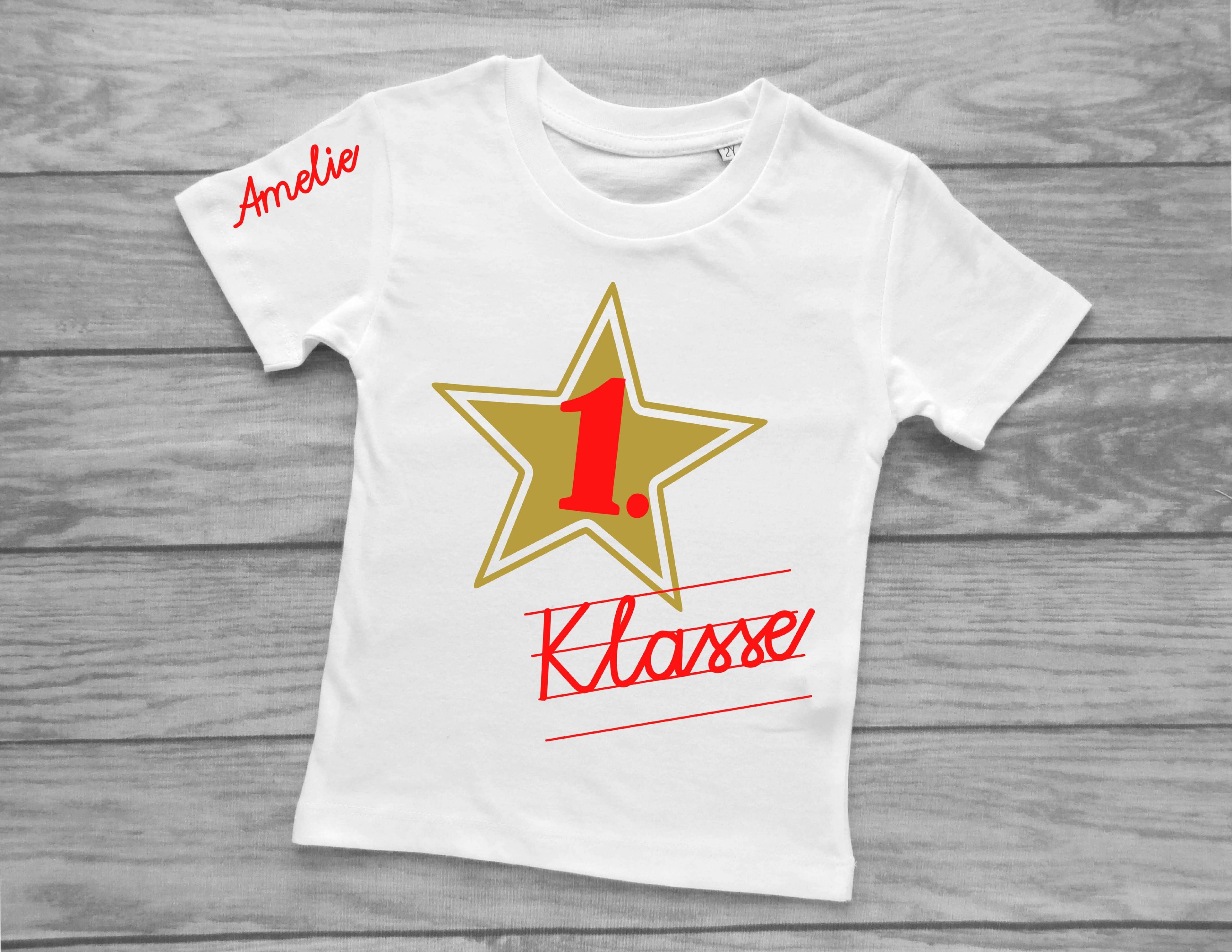 weißes T-Shirt für Einschulung, bedruckt mit Schreibschrift 1. Klasse und Name in vielen verschiedenen Farben und goldenem Stern