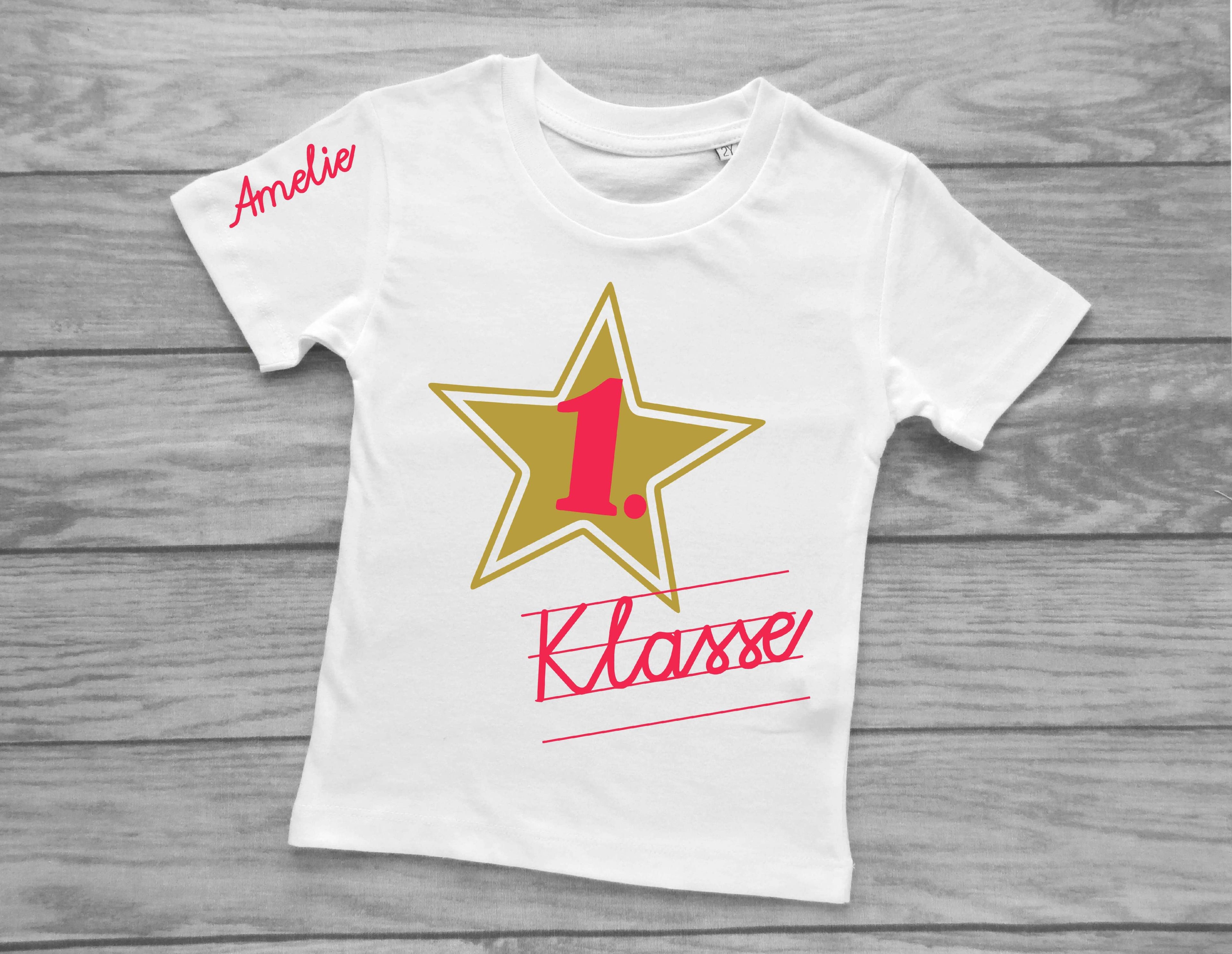 weißes T-Shirt für Einschulung, bedruckt mit Schreibschrift 1. Klasse und Name in pink und goldenem Stern