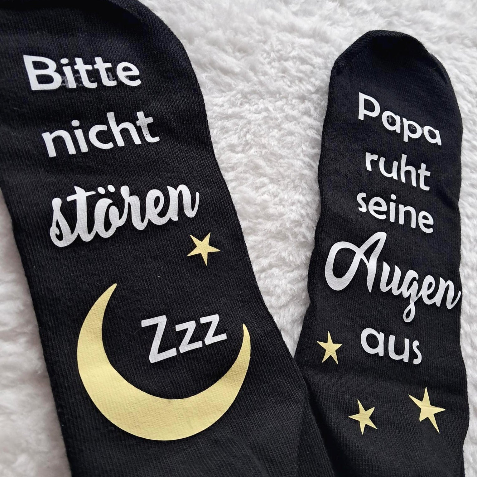 Detailbild liegende schwarze Socken, bedruckt unter der Fußsohle mit Bitte nicht stören. Papa/Mama ruht sein/ihre Augen aus.