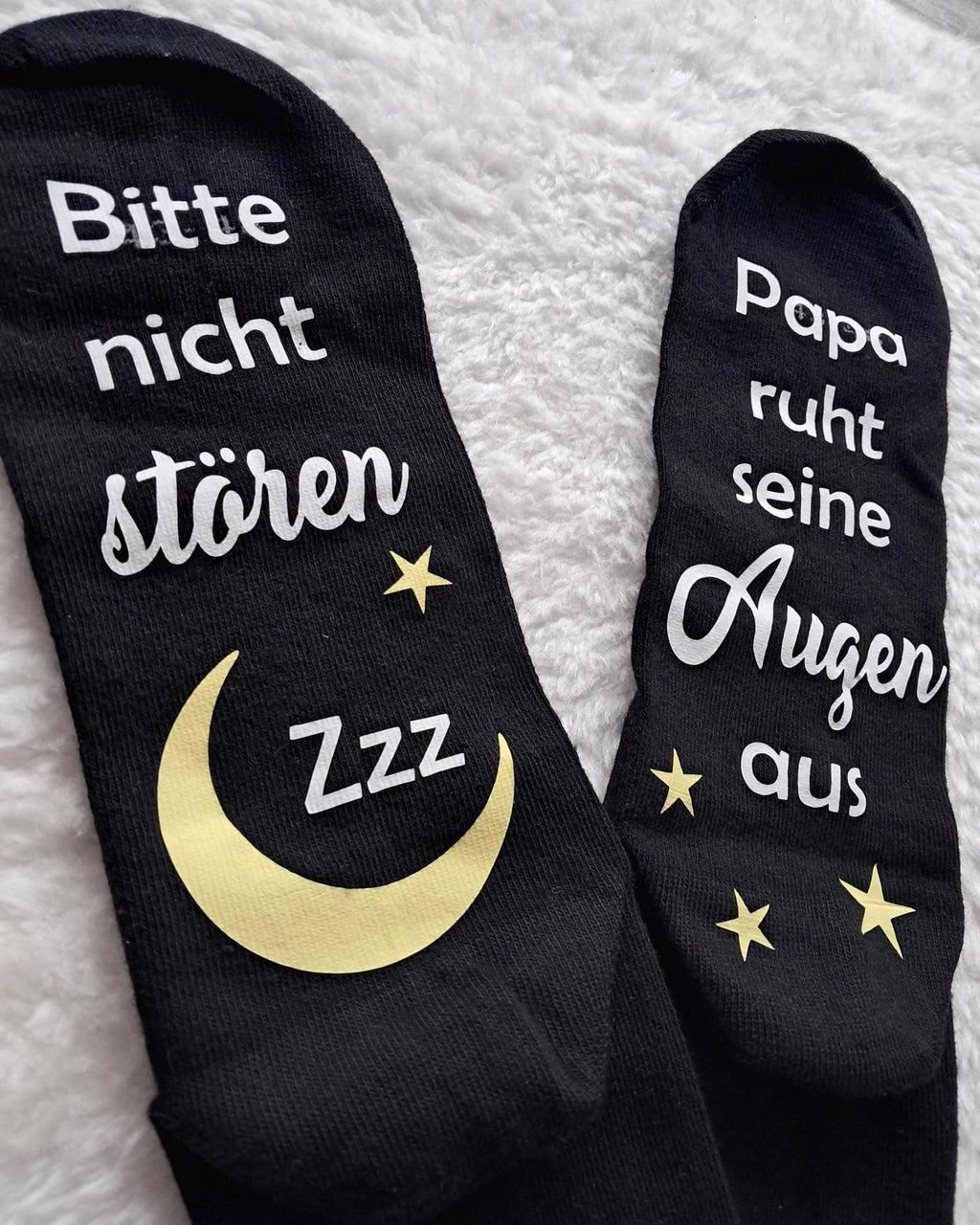 Detailbild liegende schwarze Socken, bedruckt unter der Fußsohle mit Bitte nicht stören. Papa/Mama ruht sein/ihre Augen aus.