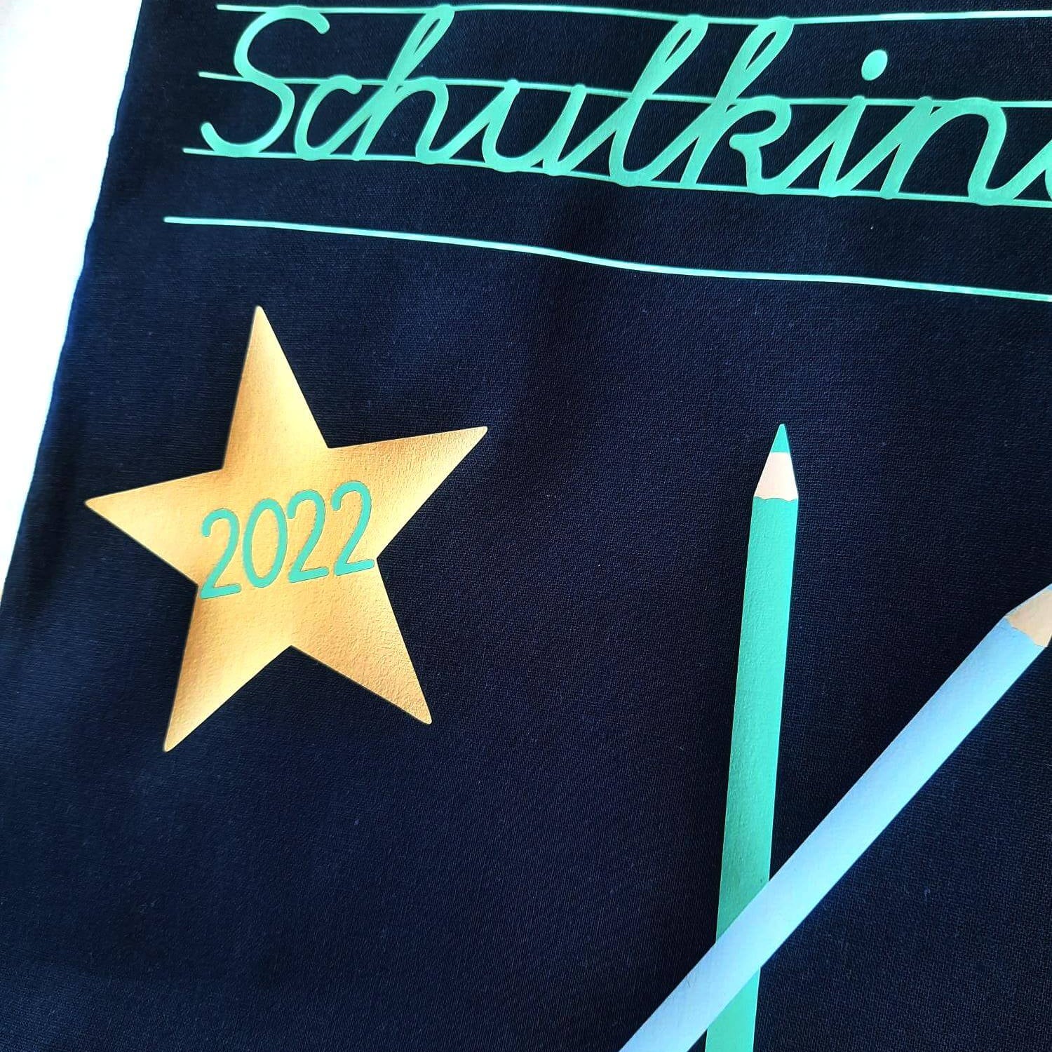 nahes Detail kleine navi farbene Tasche in Apotheker-Größe bedruckt mit Schulkind in Schreibschrift und Name in mint-gold