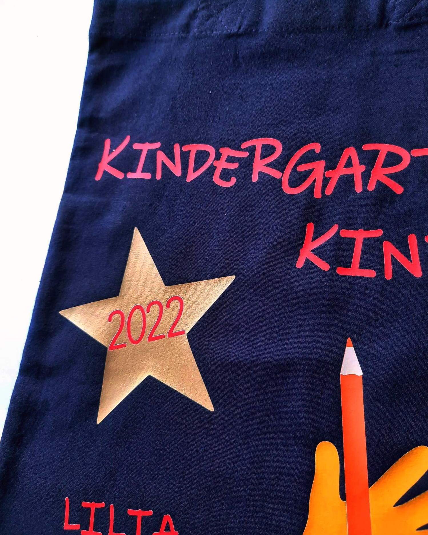Detail goldener Stern auf Kindertasche, bedruckt mit Kindergartenkind und Name in rot für KITA-Anfang 